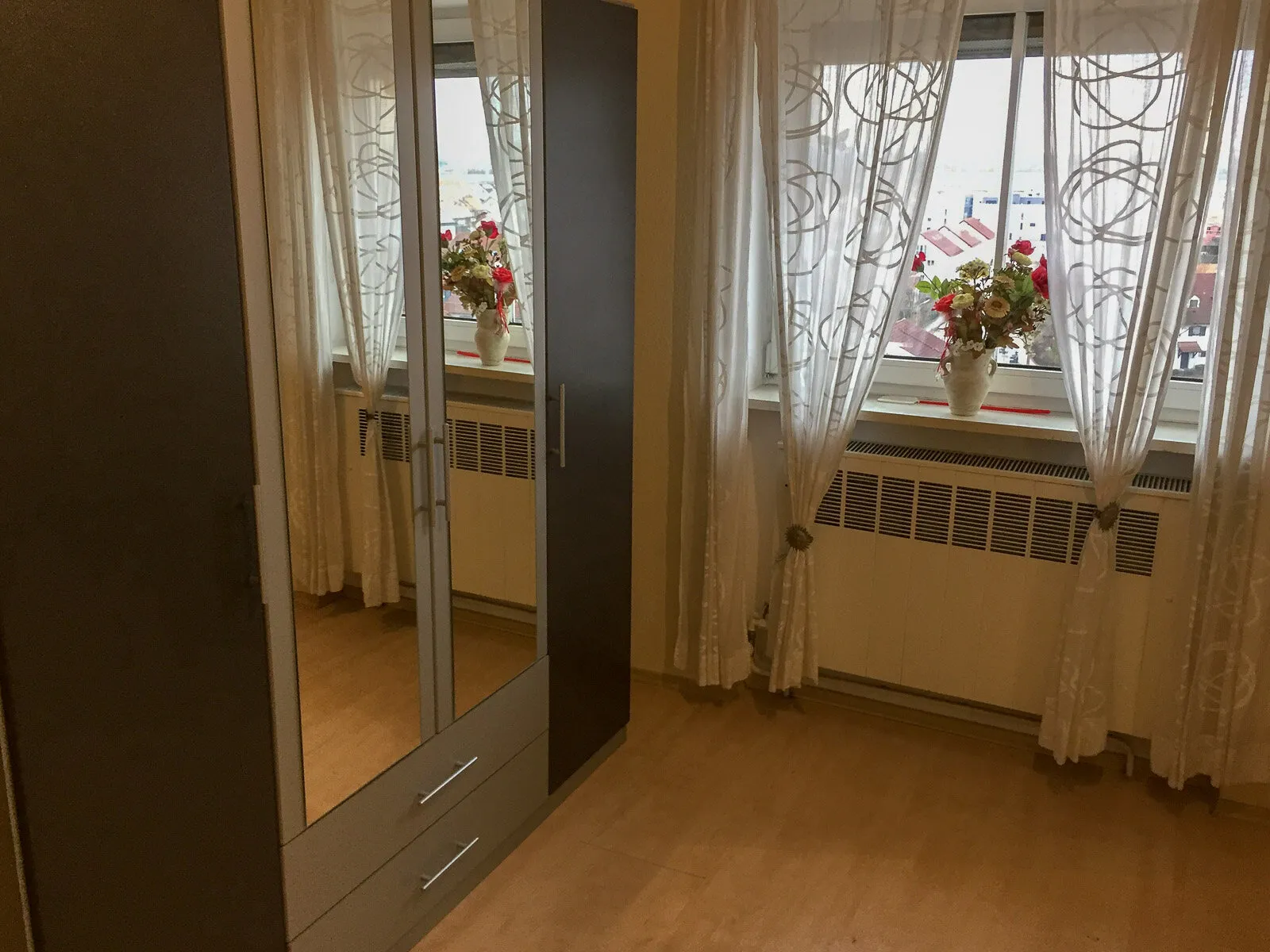 Zimmer mit Spiegelschrank und Blumenfenster