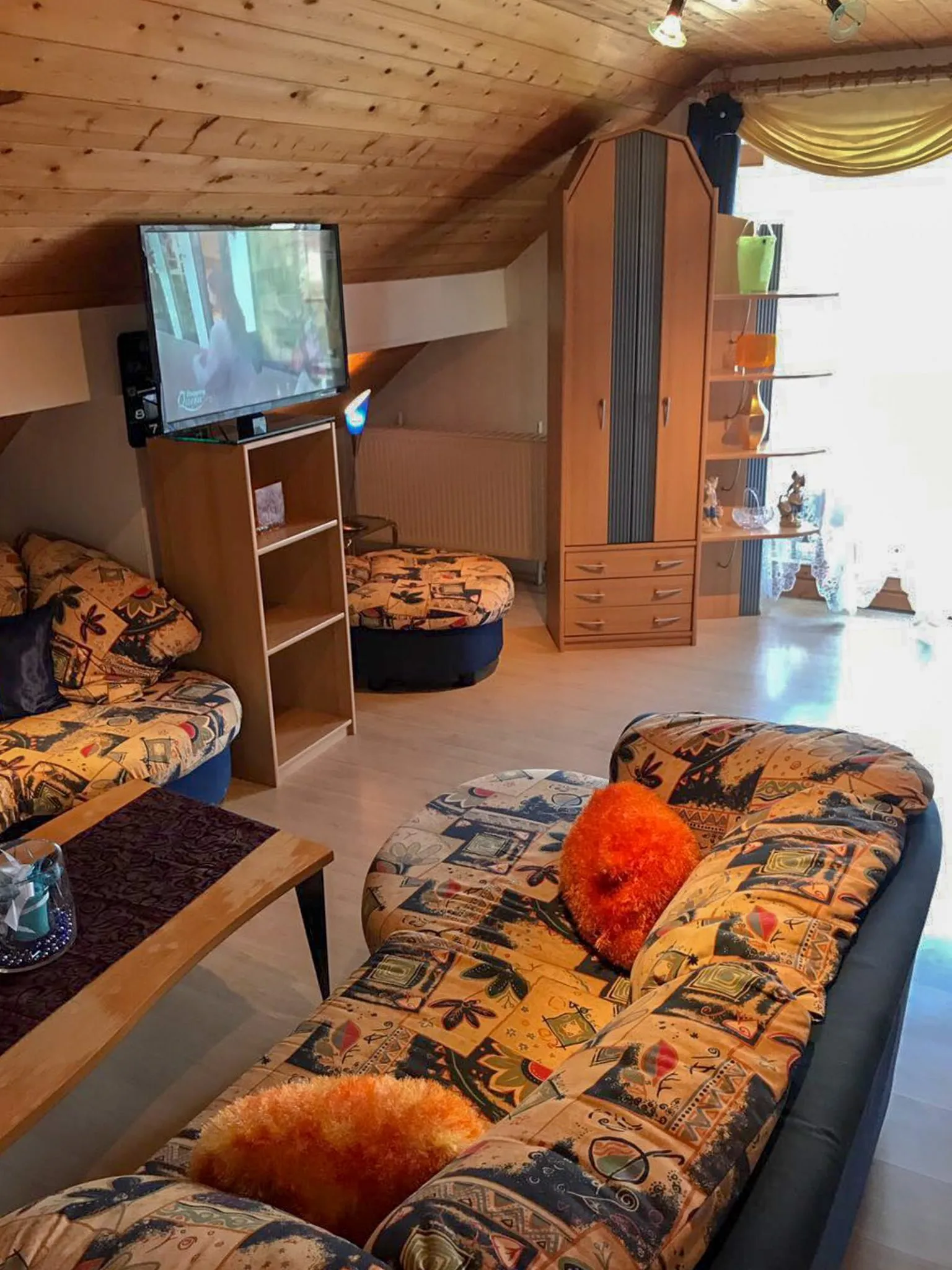Wohnbereich mit gemusterter Couch unter Dachschräge
