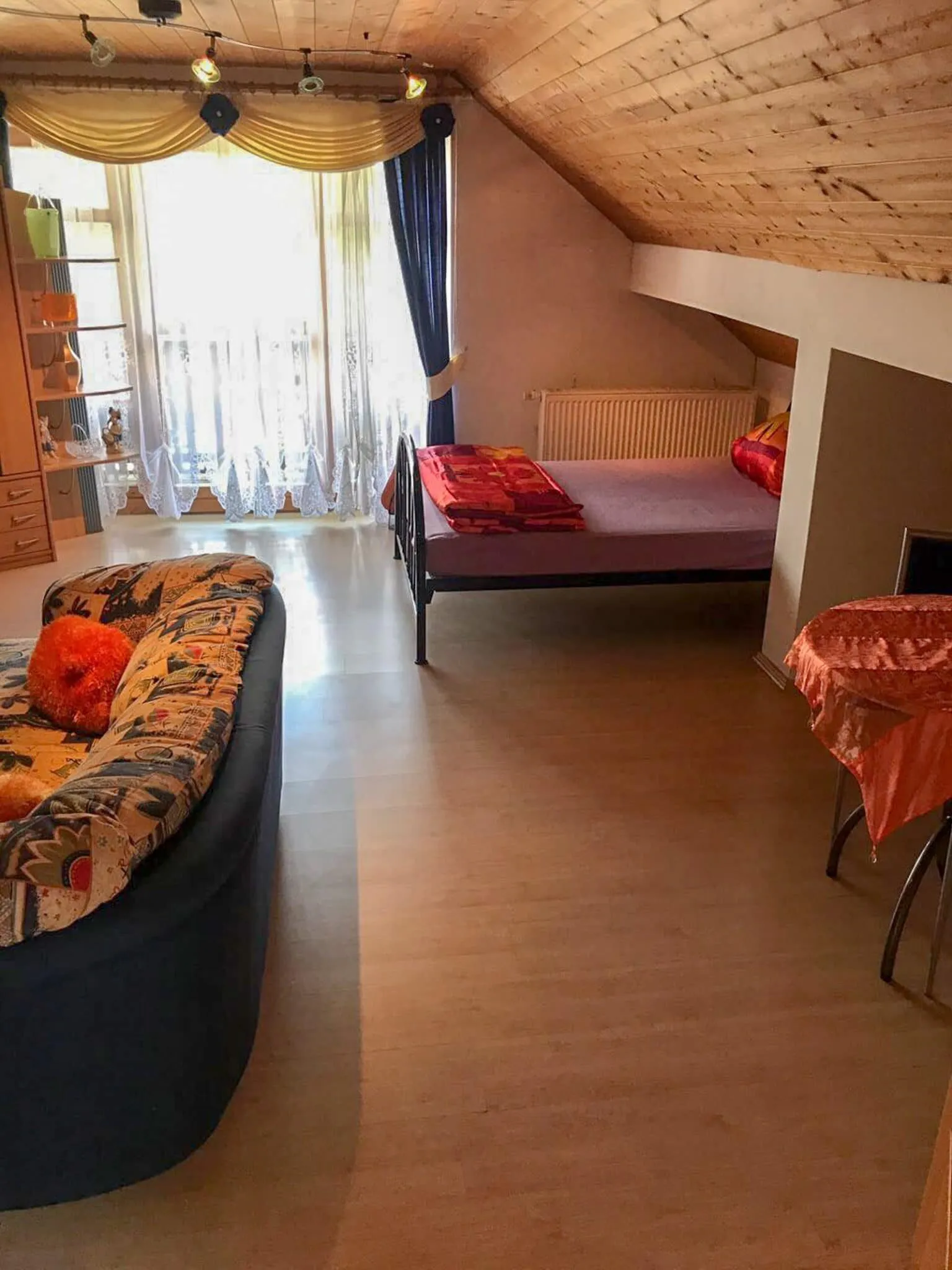Wohnbereich mit französischem Bett unter der Dachschräge